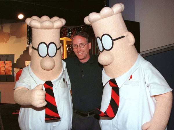 FILE PHOTO: Scott Adams, the creator of "Dilbert", the cartoon character that lampoons the absurdities of corporate life, poses with two "Dilbert" characters at a party January 8, 1999 in Pasadena. The party celebrated the new half-hour animated series "Dilbert", which  debuts on the UPN television network January 25./File Photo
