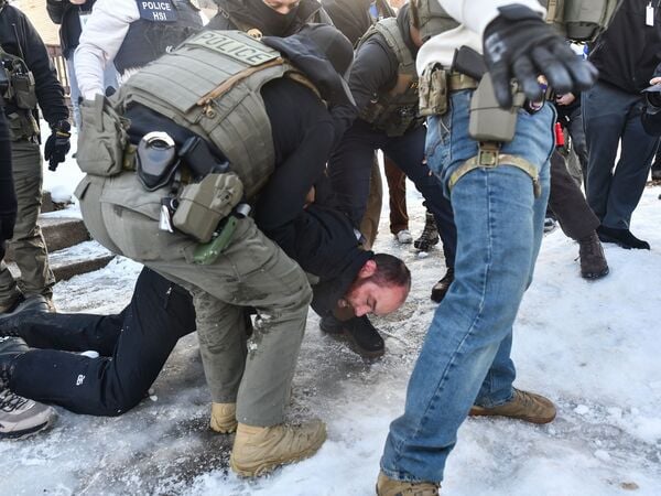 ICE and other federal officers detain a person during protests as ICE operates in a residential neighborhood in Minneapolis, Minnesota, on January 13, 2026. Hundreds more federal agents were heading to Minneapolis, the US homeland security chief said on January 11, brushing aside demands by the Midwestern city's Democratic leaders to leave after an immigration officer fatally shot a woman protester. In multiple TV interviews, US Homeland Secretary Kristi Noem defended the actions of the officer who shot and killed 37-year-old Renee Nicole Good, whose death has sparked renewed protests nationwide against President Donald Trump's immigration crackdown. (Photo by Octavio JONES / AFP)