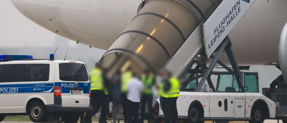 Menschen besteigen ein Flugzeug der Qatar Airways, vor dem Fahrzeuge der Bundespolizei stehen, auf dem Vorfeld am Flughafen Leipzig/Halle. 