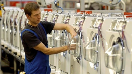 An einer Produktionsstraße für Waschautomaten arbeitet ein Miele-Mitarbeiter in Gütersloh (Archivbild).