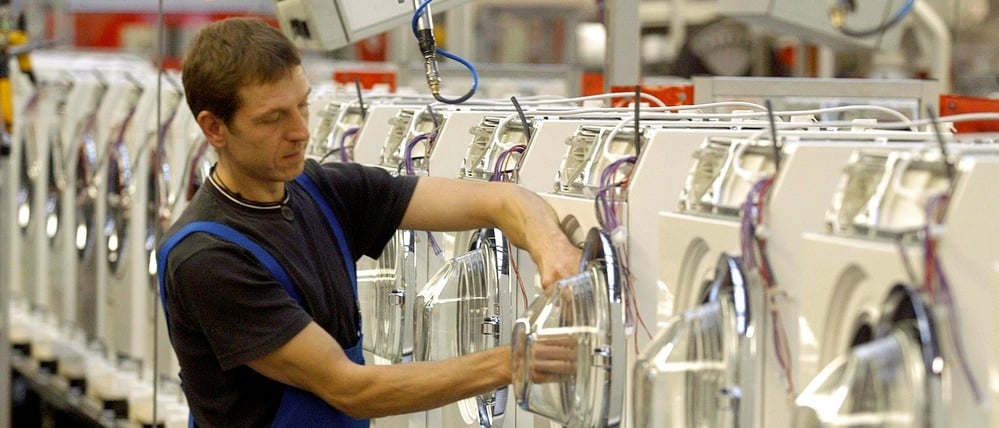 An einer Produktionsstraße für Waschautomaten arbeitet ein Miele-Mitarbeiter in Gütersloh (Archivbild).