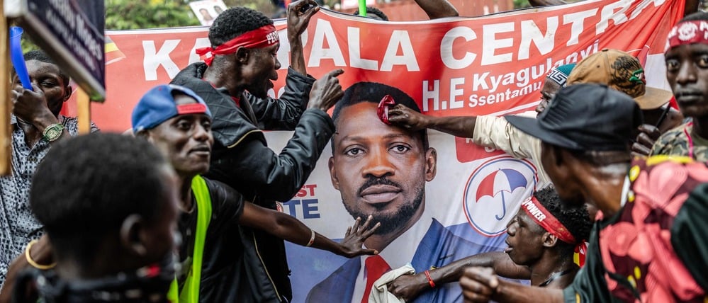 Anhänger von Bobi Wine mit einem Plakat ihres Kandidaten.