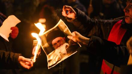 Auf einer Solidaritätskundgebung für die protestierenden Menschen im Iran in Berlin zünden junge Frauen ein Foto von Khamenei an.