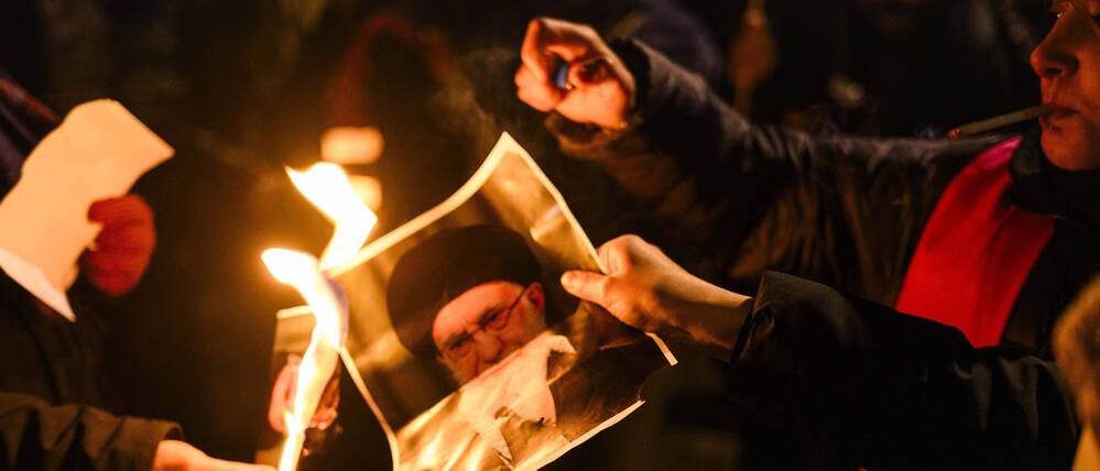 Auf einer Solidaritätskundgebung für die protestierenden Menschen im Iran in Berlin zünden junge Frauen ein Foto von Khamenei an.
