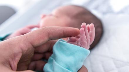 Ein Vater hält die Hand eines wenige Tage alten Jungen. 