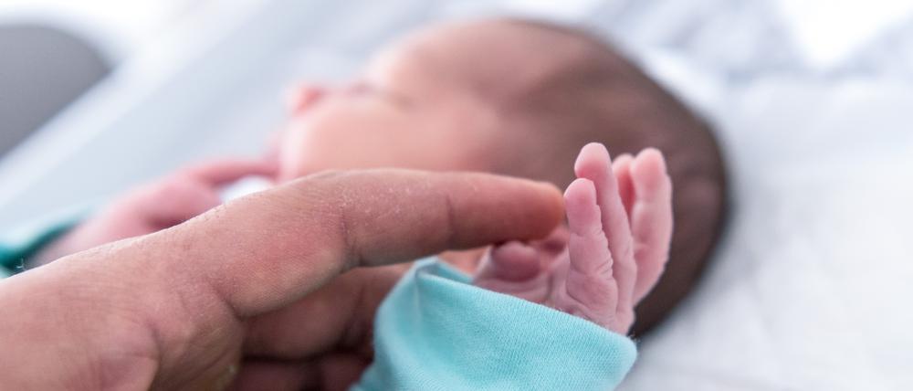 Ein Vater hält die Hand eines wenige Tage alten Jungen.