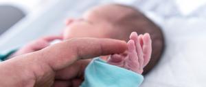 Ein Vater hält die Hand eines wenige Tage alten Jungen. 