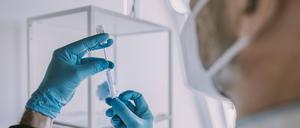 Doctor taking vaccination in syringe while standing at examination room during COVID-19 model released Symbolfoto property released MFF07396