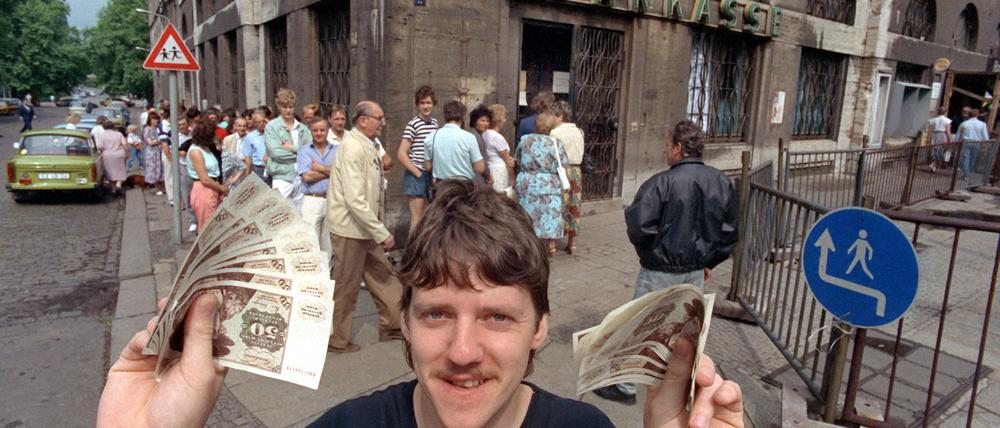 Nach langem Schlangestehen vor einer Leipziger Bank freut sich dieser junge Mann über seine D-Mark-Banknoten am 1. Juli 1990