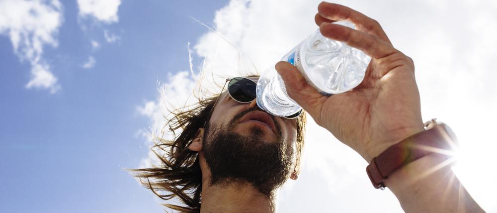 Low Angle View Of Man Wearing Sunglasses And Drinking Water Against Sky