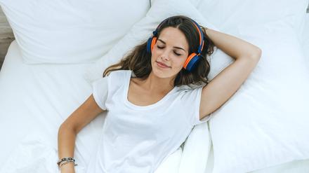 Young woman sleeping in bed at home with headphones model released Symbolfoto property released PUBLICATIONxINxGERxSUIxAUTxHUNxONLY KIJF02565