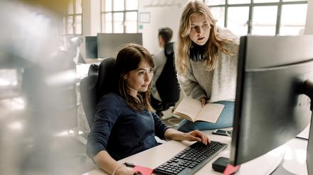 Female colleagues discussing while sitting in office