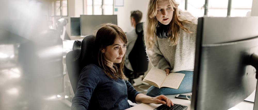 Female colleagues discussing while sitting in office