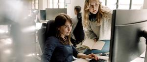 Female colleagues discussing while sitting in office