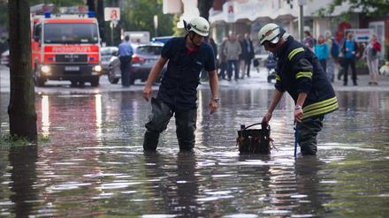 Drakestraße unter Wasser: Nach einem Starkregen im Sommer 2011 versuchen Feuerwehrmänner einen verstopften Gully frei zu bekommen.