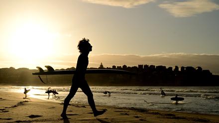 Surfer genießen den Sonnenaufgang am Bondi Beach.