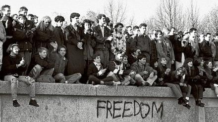 Berliner sitzen 1989 auf der Mauer am Brandenburger Tor.