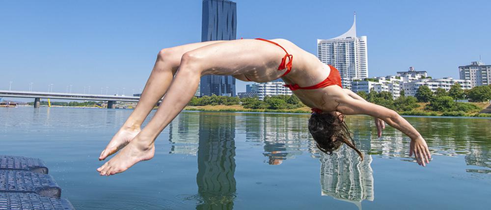 Auf der Donauinsel baden die Wiener:innen mit Blick auf die Skyline. 