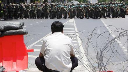 Ein einsamer Demonstrant in Bangkok beobachtet den Aufmarsch von Polizeieinheiten.