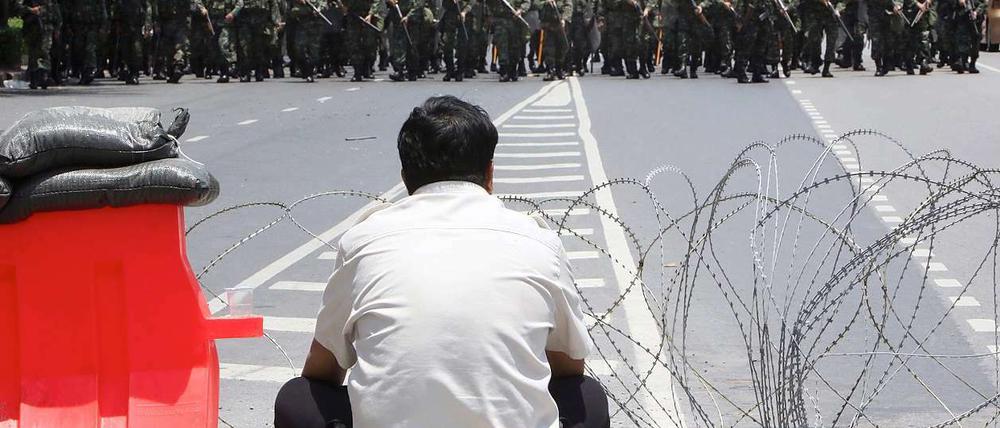 Ein einsamer Demonstrant in Bangkok beobachtet den Aufmarsch von Polizeieinheiten.
