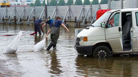 Feuerwehrmänner decken am Donnerstag mit Sandsäcken an der Promenade in Frankfurt an der Oder Kanaldeckel ab, aus denen Grundwasser hoch drückt.