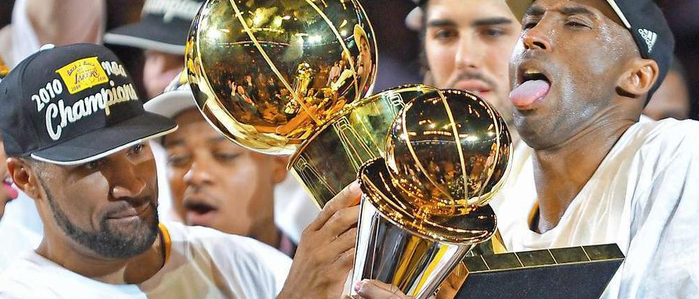  Pokalrunde: Lakers-Spieler Kobe Bryant (rechts) hält die Trophäe für den "Most Valuable Player", sein Teamkollege Derek Fisher reicht ihm den Teampokal dazu.