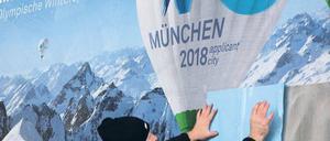 Kleben für Olympia. Ein Helfer befestigt das Logo der Münchner Bewerbung für die Winterspiele 2018 auf einen Plakatträger. Foto: dpa