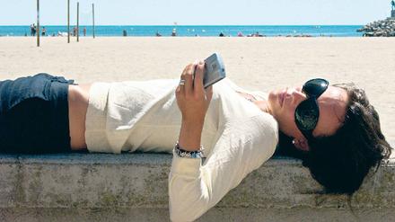 Entspannt am Strand. Wer auch nach dem Urlaub keinen Stress mit der Handyrechnung erleben will, muss die Kostenfallen kennen. Foto: mauritius images