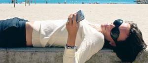 Entspannt am Strand. Wer auch nach dem Urlaub keinen Stress mit der Handyrechnung erleben will, muss die Kostenfallen kennen. Foto: mauritius images