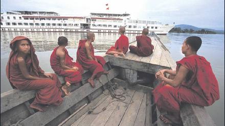 Begegnung auf dem Irrawaddy. So, wie die Mönche in ihrem Kahn über das weiße Schiff staunen, haben die Kreuzfahrtgäste immer wundersame Aussichten. 