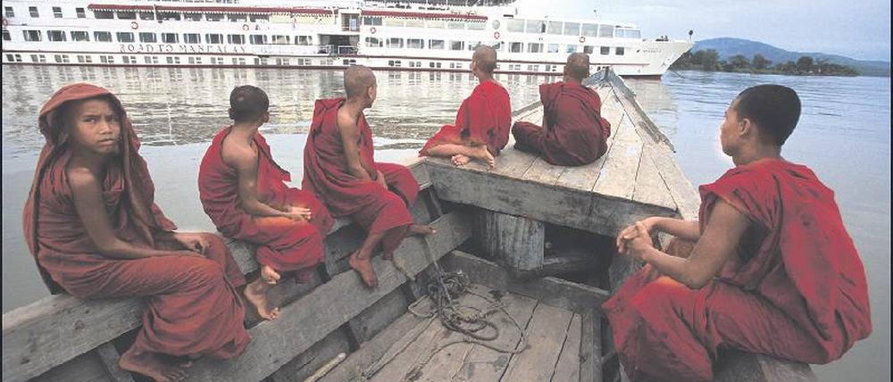 Begegnung auf dem Irrawaddy. So, wie die Mönche in ihrem Kahn über das weiße Schiff staunen, haben die Kreuzfahrtgäste immer wundersame Aussichten. 