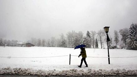 Wo ist der goldene Herbst geblieben? Eine Frau läuft am Montag bei Ettal (Oberbayern) durch die schneebedeckte Landschaft.