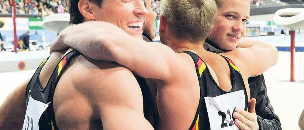 Zusammen ist man weniger allein. Philipp Boy, Eugen Spiridonov und Fabian Hambüchen (von links) freuen sich über ihre WM–Bronzemedaille im Mannschaftswettbewerb. Foto: dpa