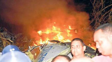 Menschen aus umliegenden Orten helfen bei den Rettungsarbeiten am brennenden Wrack. Foto: AFP PHOTO/HO/ESCAMBRAY NEWSPAPER