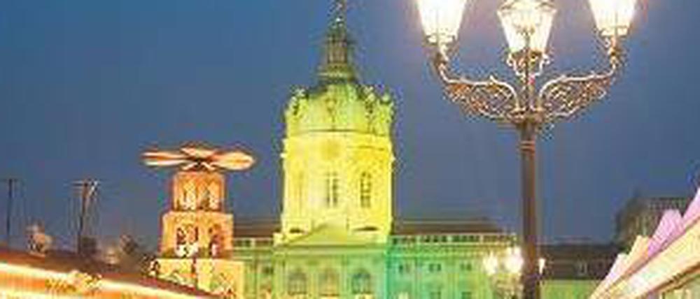 Weihnachtsmarkt am Schloss Charlottenburg mit bunt angestrahltem Schlossgebäude.