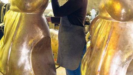 Noch ohne Rot. Die Ziseleurin Gabi Freudenreich begutachtet die bronzenen Rotkäppchenfiguren. 400 Kilogramm bringt jedes Mädchen auf die Waage. Foto: dpa/Pleul