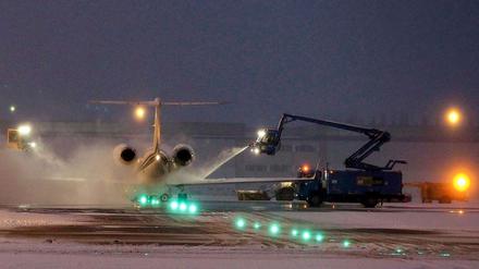 Flughafen bei Nacht. Enteisungsmannschaften arbeiten ohne Unterbrechung auf dem Rollfeld.