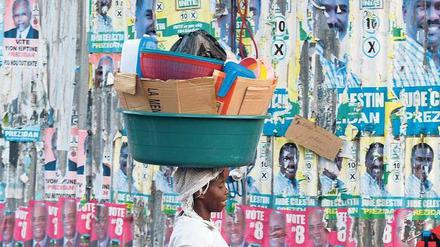 Reste einer missglückten Wahl. Eine Frau läuft an einer Wand mit Plakaten in der Hauptstadt Port-au-Prince vorbei. Foto: Reuters