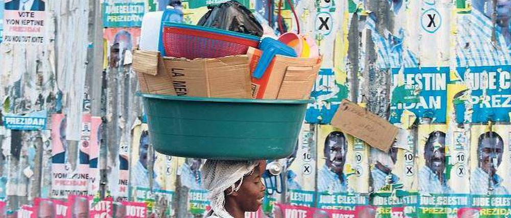 Reste einer missglückten Wahl. Eine Frau läuft an einer Wand mit Plakaten in der Hauptstadt Port-au-Prince vorbei. Foto: Reuters