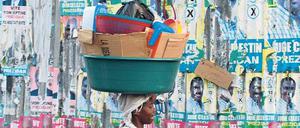Reste einer missglückten Wahl. Eine Frau läuft an einer Wand mit Plakaten in der Hauptstadt Port-au-Prince vorbei. Foto: Reuters