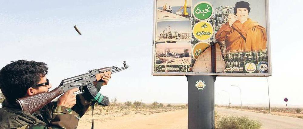 Freie Schussbahn. Im Osten Libyens, wie hier in Ras Lanuf, haben die Rebellen Gaddafis Truppen vertrieben. Symbole seiner Herrschaft werden zerstört. 