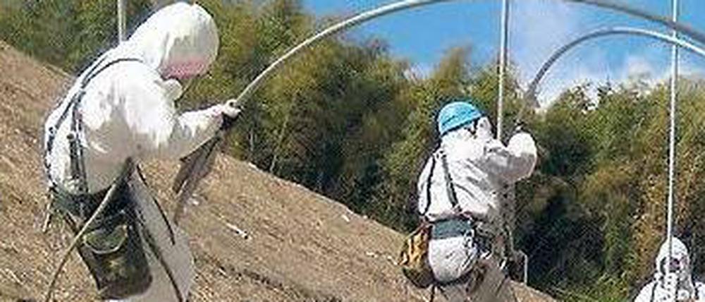 Tepco-Arbeiter in Schutzanzügen versuchen im Akw-Komplex Fukushima, Stromleitungen wiederherzustellen.