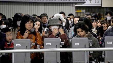 Nach dem Beben fielen in Tokio Internetverbindungen und mobile Telefone aus. Hier scharen sich Pendler um Festnetz-Apparate.
