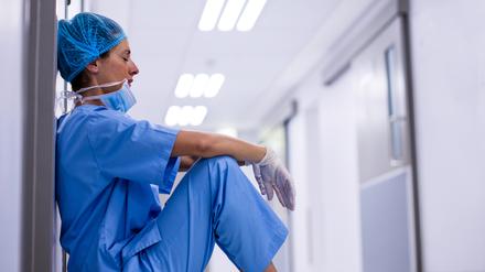 Sad surgeon sitting on floor in corridor at hospital