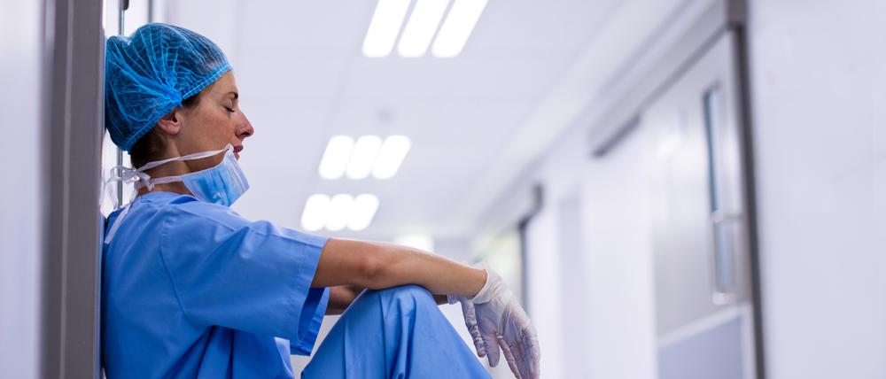 Sad surgeon sitting on floor in corridor at hospital
