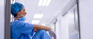Sad surgeon sitting on floor in corridor at hospital
