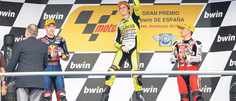 Glückwunsch aus erlauchter Hand. Während Nicolas Terol den Heimsieg in der 125er-Klasse bejubelt, macht Jonas Folger (l.) die Bekanntschaft von König Juan Carlos. Foto: Reuters
