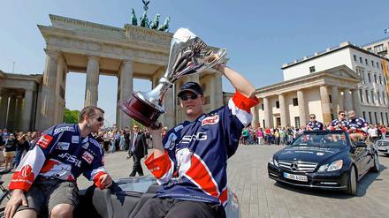 Derrick Walser (l) und Steve Walker von den Eisbären Berlin zeigen am 23.04.2011 vor dem Brandenburger Tor in Berlin den Meisterpokal. 