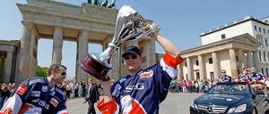 Derrick Walser (l) und Steve Walker von den Eisbären Berlin zeigen am 23.04.2011 vor dem Brandenburger Tor in Berlin den Meisterpokal. 