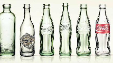 Alte Tante Cola. Bis zur Konturflasche war es ein langer Weg. Vorbild war angeblich der Körper einer Frau. Erfunden haben soll sie ein Buchhalter, der auch den geschwungenen Schriftzug kreierte.